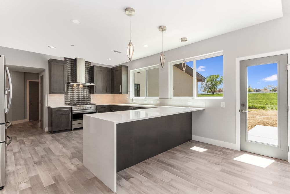 Modern kitchen featuring dark cabinets, stainless steel appliances, and large windows with outdoor views.