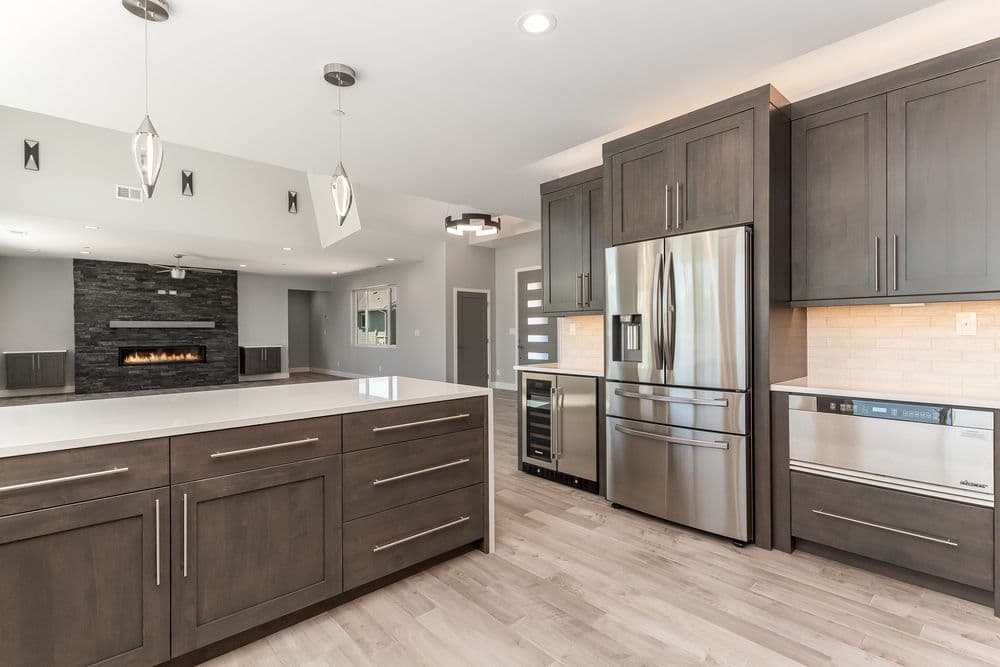 Modern kitchen featuring sleek dark cabinetry, stainless steel appliances, and an island with white countertop.