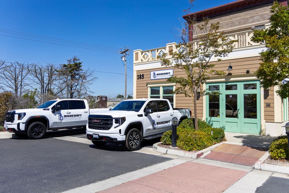 Two white pickup trucks branded with the "Minecart" logo parked outside a modern building.